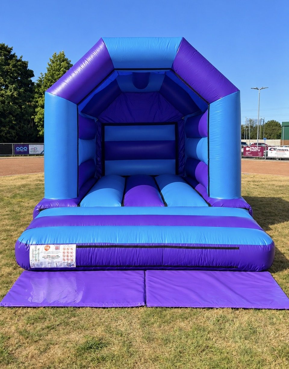 Blue and purple bouncy castle with safety mats on a field