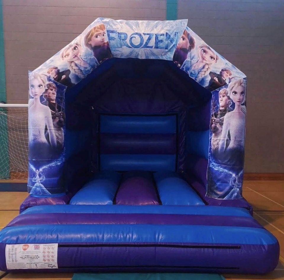 Blue and purple Frozen themed bouncy castle set up in a sports hall