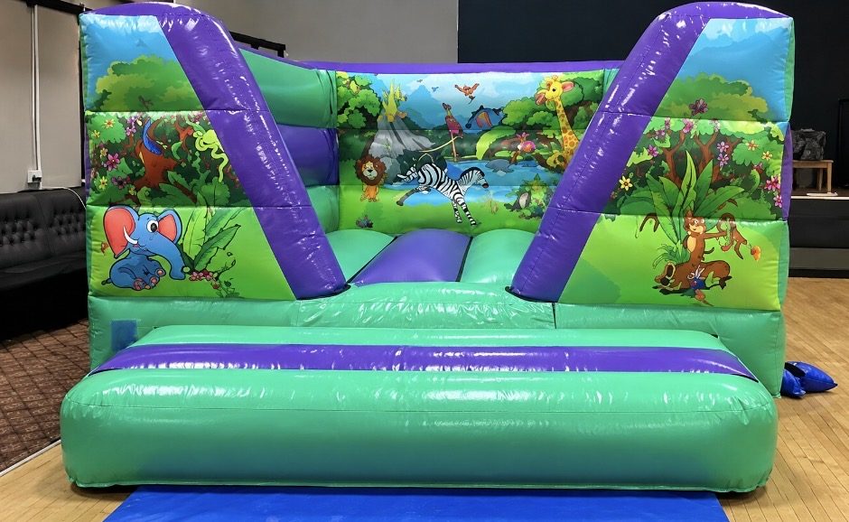 Green and purple bouncy castle with jungle animal artwork including an elephant, lion, zebra and giraffe