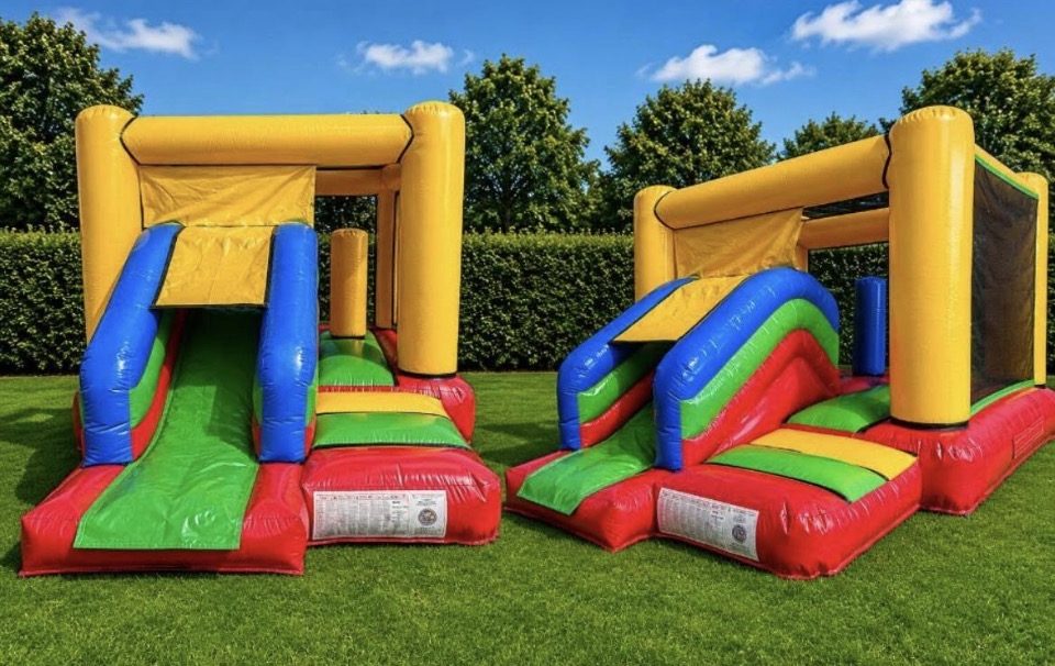 Two red, yellow, green and blue bouncy castles with slides on a lawn