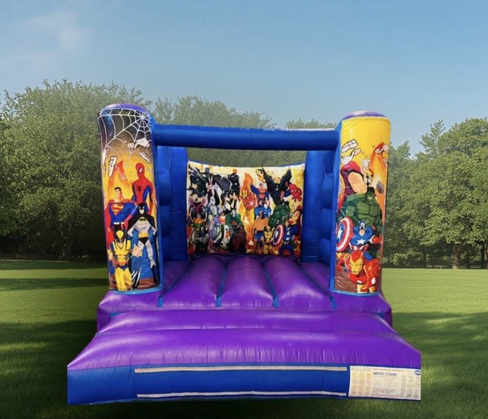 Blue and purple superhero themed bouncy castle in a park