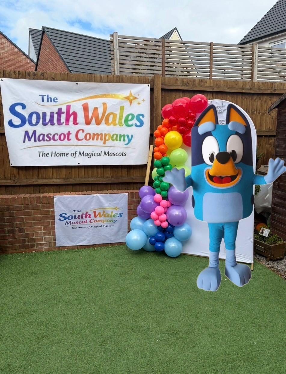 Bluey lookalike mascot waving next to a rainbow balloon garland
