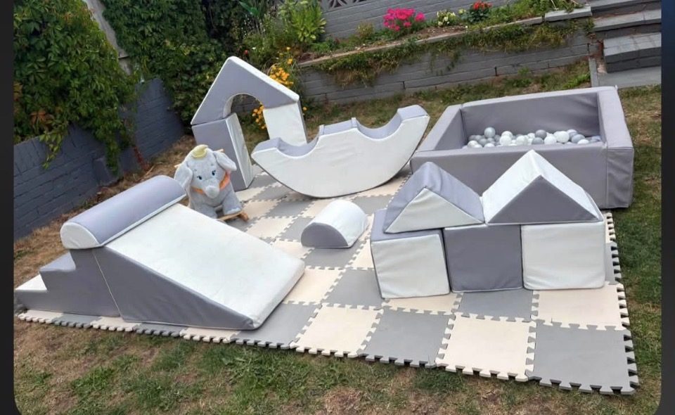 Grey and white soft play set with ball pit, slide, rocker and blocks on foam mats